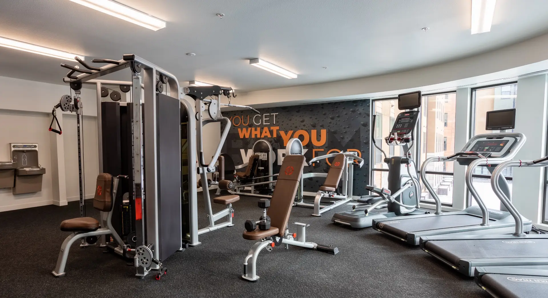 fitness center with treadmills, elliptical, free weight bench, and weight machine.