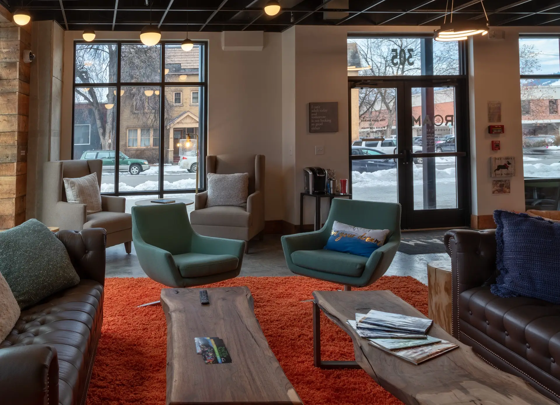 ROAM student living lobby with ample lounge seating, an orange rug and floor to ceiling windows.